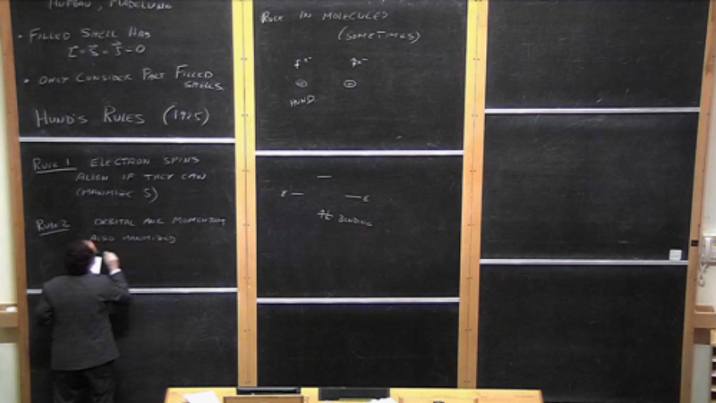A lecturer writing on vertical blackboards.
